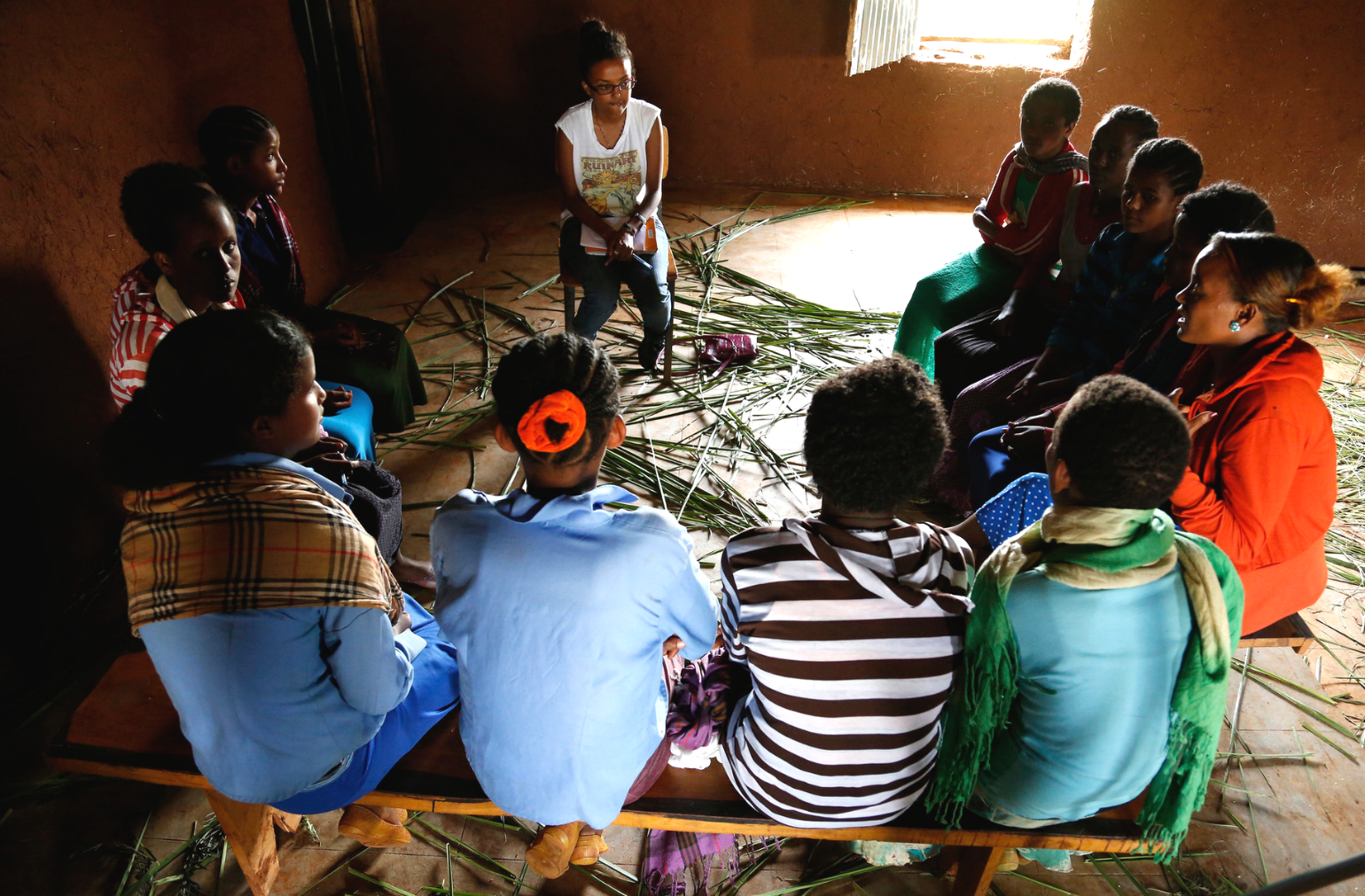 Photo of a community group discussion; a group of women inside a room sat in circle. 