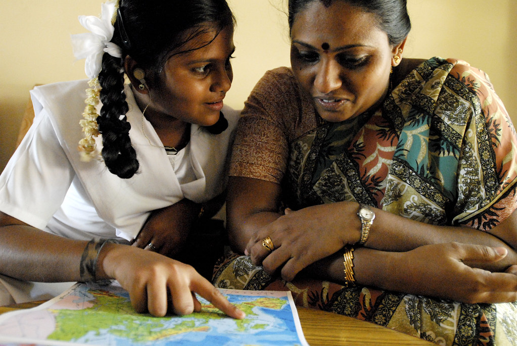Teacher and a young girl looking at a map on a table. 