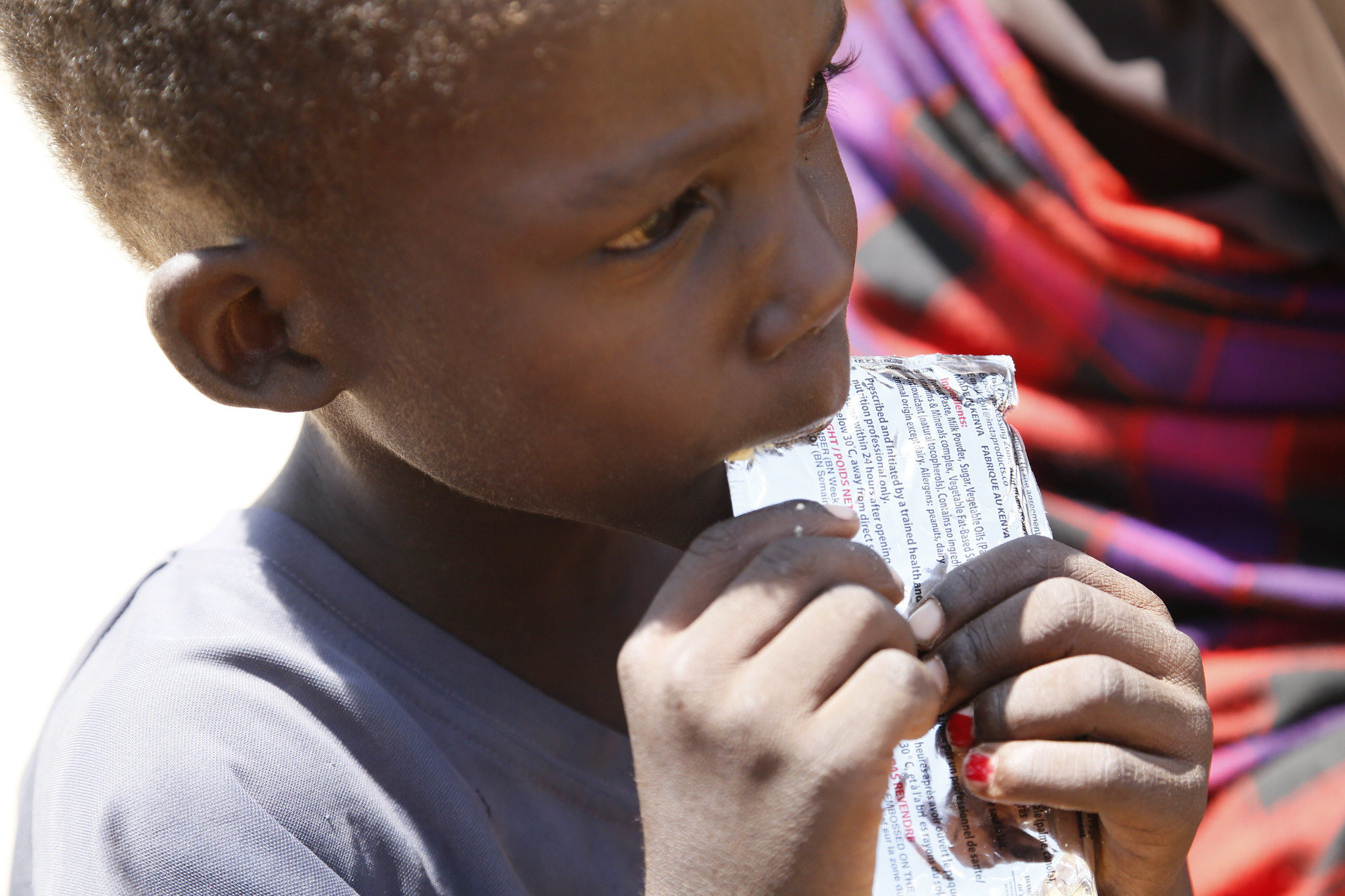 Photo of a young boy eating from a high nutrition pack.