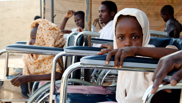 Young girl sat in a wheelchair looking at the camera. 